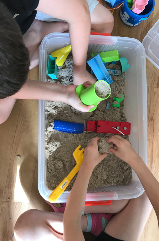 trauernde Kinder spielen an Indoor-Sandkiste