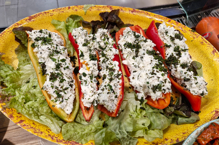 Mit Frischkäse gefüllte Spitzpaprika auf einem Teller mit Salat angerichtet